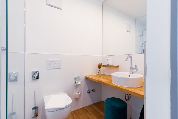 A modern bathroom with a white sink, wooden countertop, and a mirror above the sink.