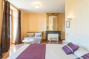 Een hotelkamer met een bed, een bank, een bijzettafeltje, een open haard en een spiegel.