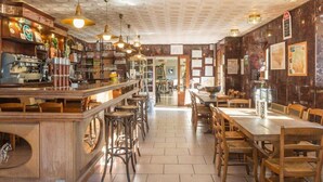 A cozy restaurant with a bar area, wooden furniture, and a patterned ceiling.