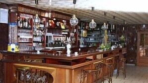 A bar area with wooden bar counter, multiple stools, and hanging light fixtures.