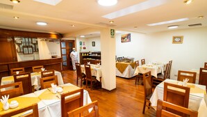 Un restaurant amb taules i caires de fusta, una zona de cuina i un senyal que indica una àrea per a fumadors.