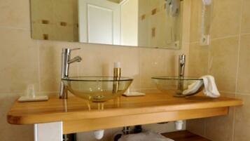 A bathroom with a wooden vanity, two glass sinks, a large mirror, and a towel rack.