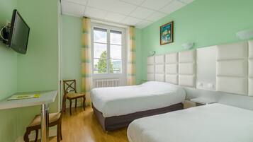 Habitación de hotel con dos camas, un escritorio, una silla, un televisor y una ventana con cortinas.