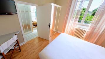 Een slaapkamer met een bed, een televisie, een bureau en een badkamer, zichtbaar door een geopende deur.