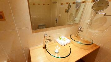 A bathroom with two glass sinks, a mirror, and a towel rack.