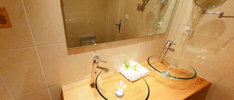 A bathroom with two glass sinks, a mirror, and a towel rack.