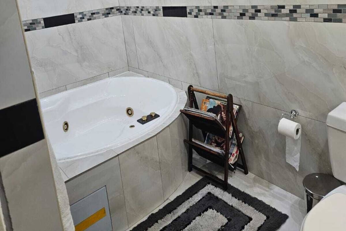 A bathroom with a bathtub, toilet, and a magazine rack.