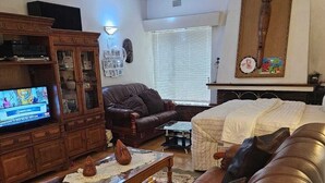 Una sala de estar con un sofá de cuero marrón, un armario de madera, un televisor y una chimenea.
