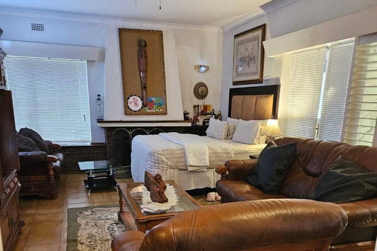 A cozy living room with a fireplace, leather sofa, and a dining area.
