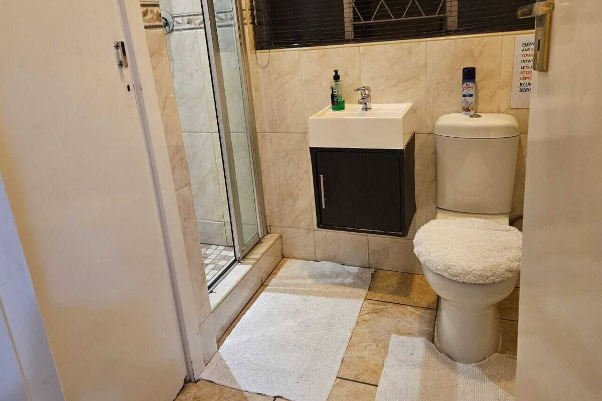 A bathroom with a glass shower door, a sink, a toilet, and a towel rack.