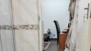 Baño con cabina de ducha de vidrio, escritorio de madera y una silla.