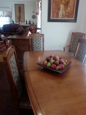 Una mesa de comedor con un frutero en el centro, rodeada de sillas con diseños.