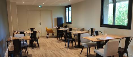 A conference room with multiple tables and chairs, a large window, and a door.