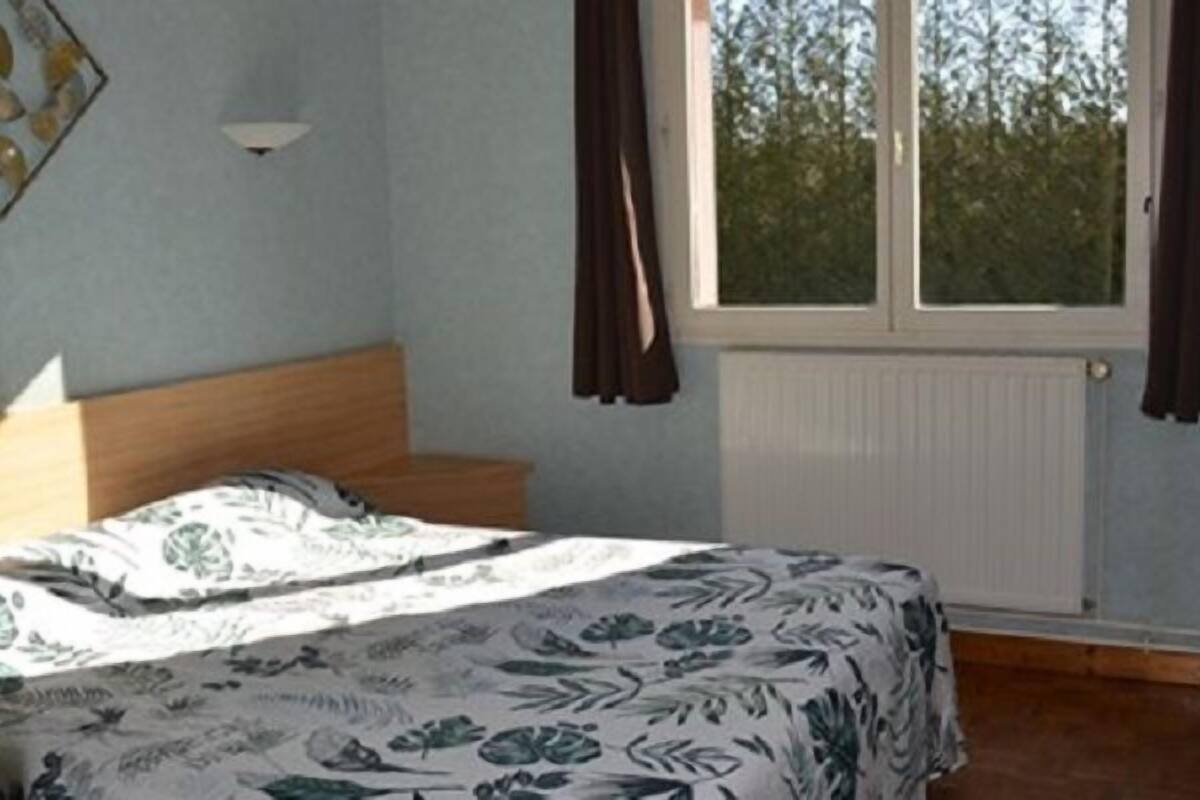 Ein Schlafzimmer mit Bett, Fenster und Heizkörper.