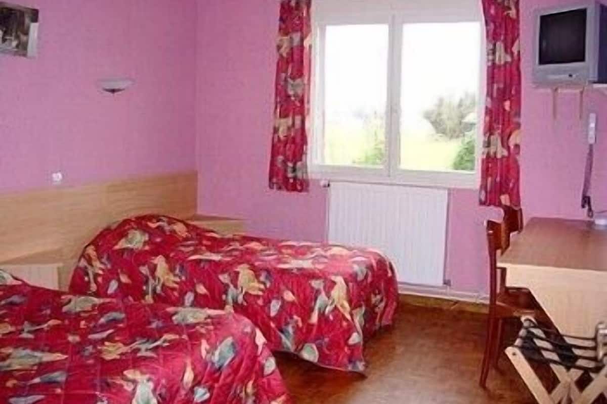 Ein Zimmer mit zwei Betten, einem Fernseher und einem Fenster mit Vorhängen.