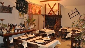 Een eetruimte met gedekte tafels, een open haard van baksteen en diverse decoratieve objecten aan de wanden.