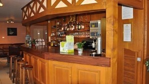Een bar met houten inrichting, krukken en verschillende flessen en glazen.