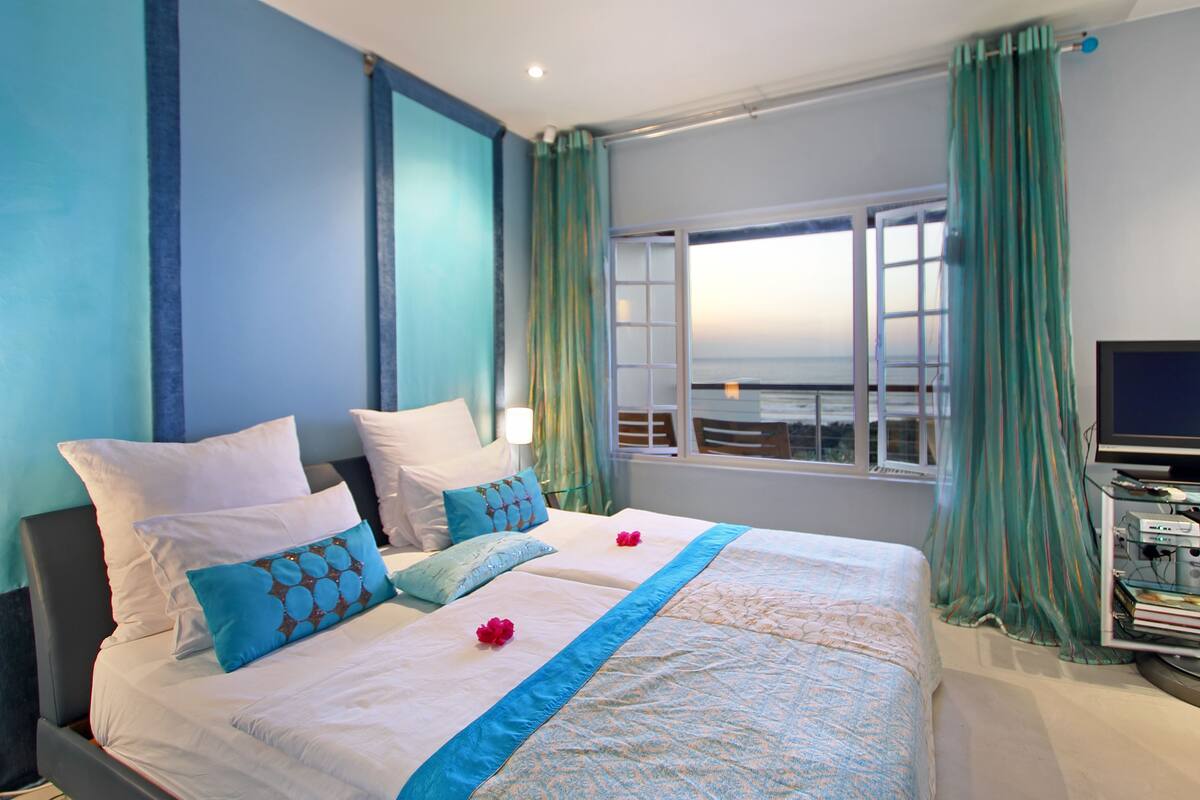 A hotel room with a large bed, two pillows, a TV, and a window with curtains.