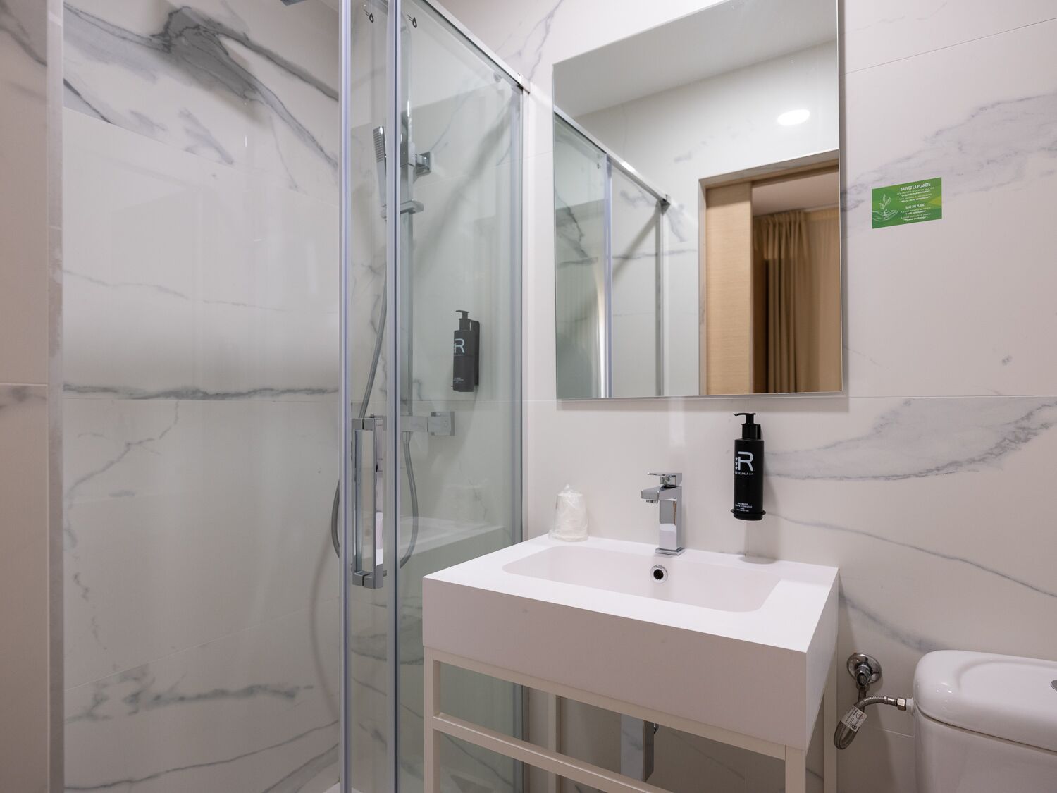 Een moderne badkamer met een douchecabine van glas, een wit wastafelmeubel en een toilet.