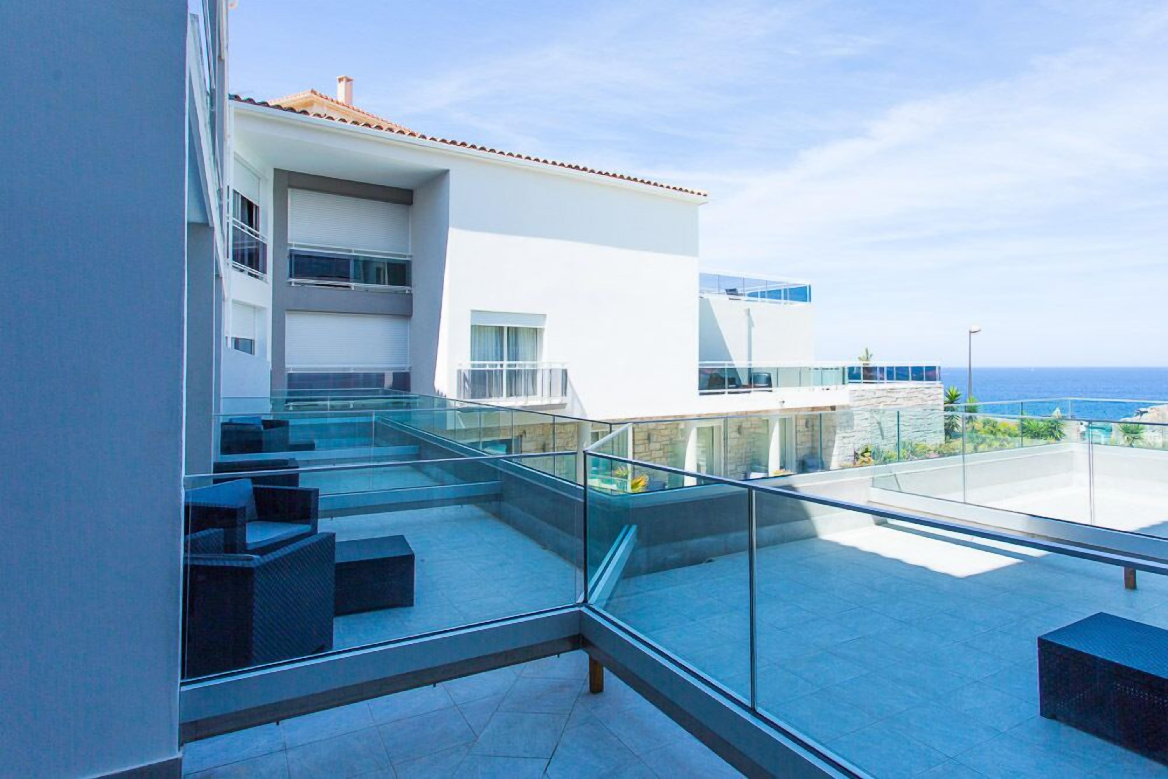 A modern building with a glass balcony overlooking the sea.