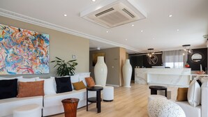 Un salon moderne avec un canapé blanc, une table basse et un grand tableau abstrait.