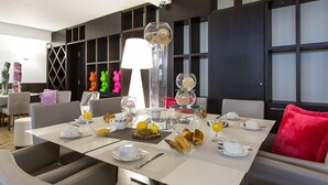 Une table mise pour le petit-déjeuner, avec une nappe, de l’assiette, des tasses et divers aliments pour le petit-déjeuner.