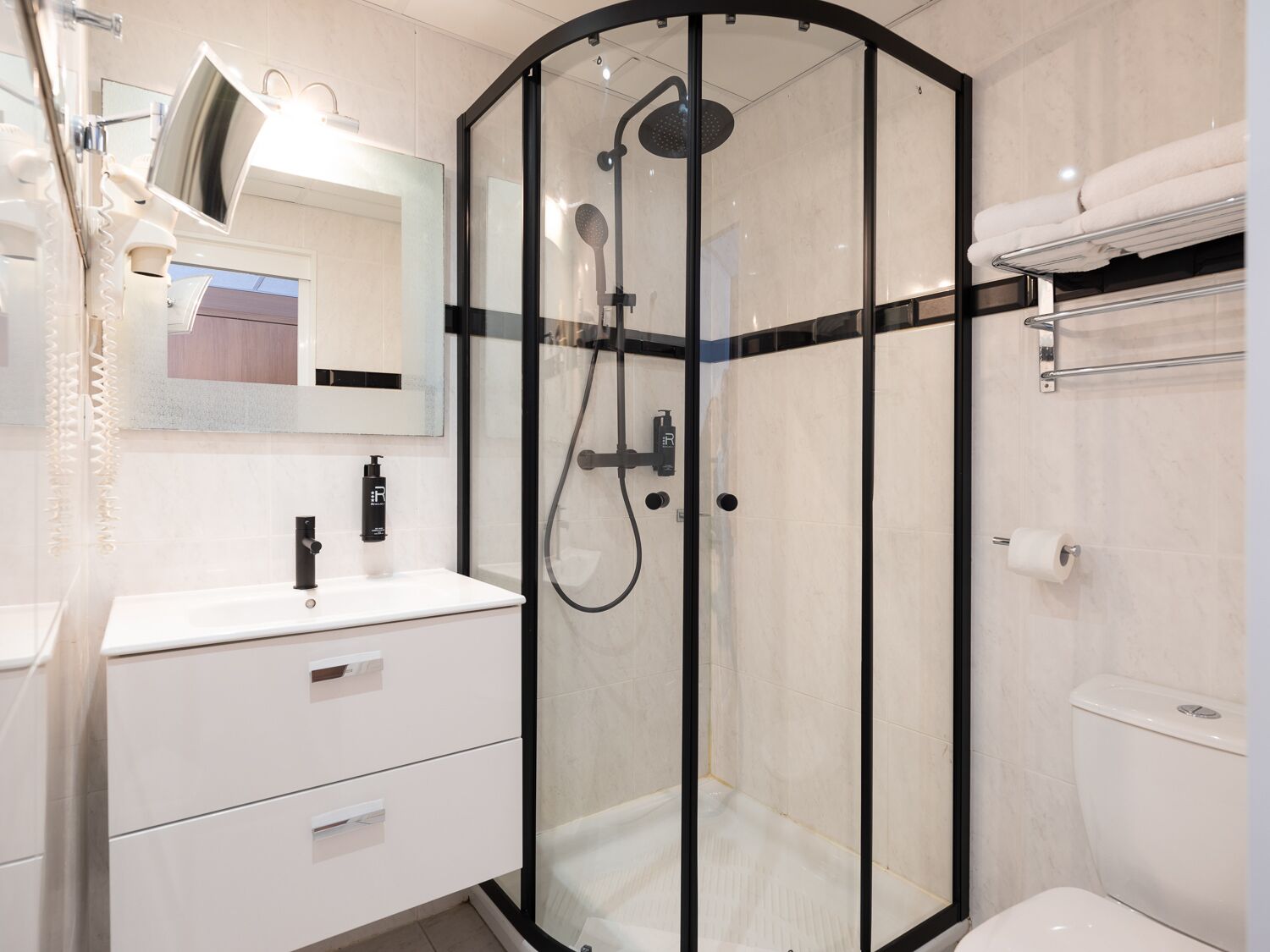 A modern bathroom with a glass-enclosed shower, a white sink, and a toilet.