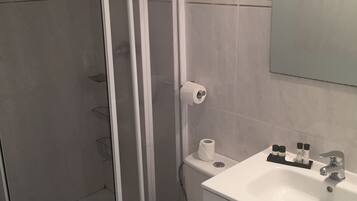 A bathroom with a toilet, a sink, and a shower enclosure.