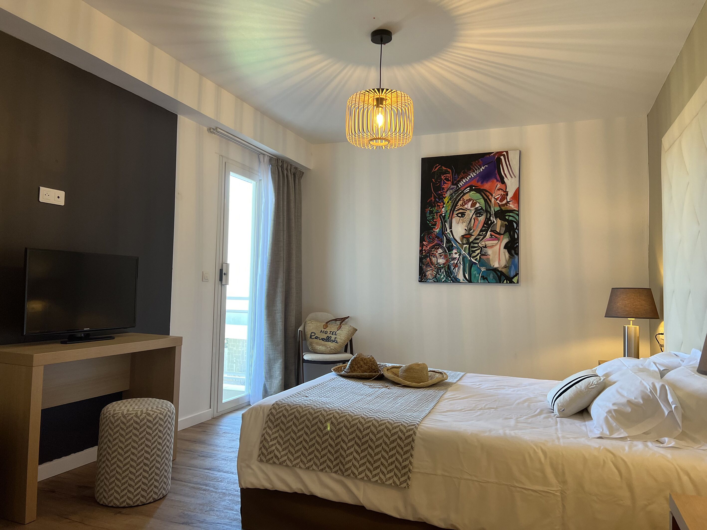 Une chambre d’hôtel avec un lit, une télévision, un tableau et une lampe.