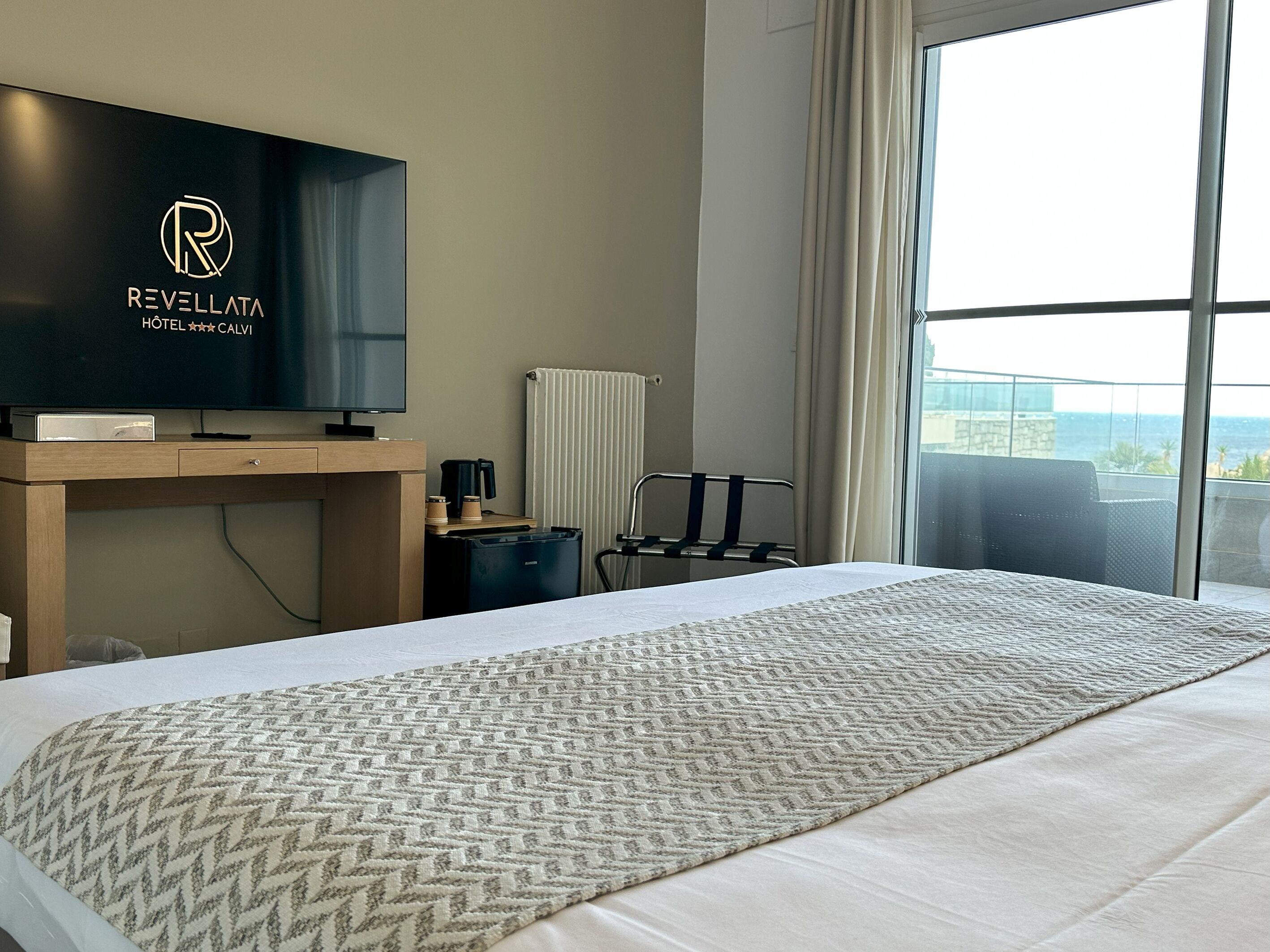 Une chambre d’hôtel avec un lit, une télévision, un bureau et une fenêtre donnant sur l’océan.