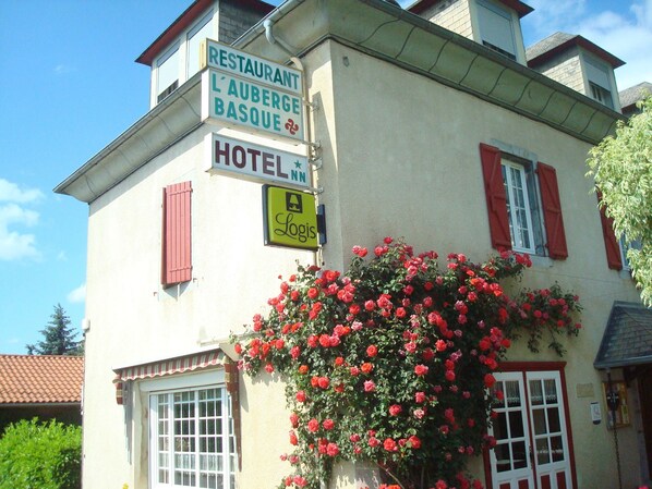 A building with signs for a restaurant, a hotel, and a logis.
