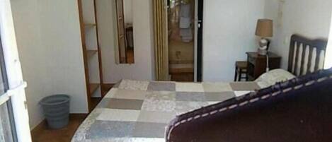 A bedroom with a bed, a chair, a desk, and a wardrobe.