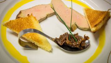 A plate with a slice of meat, two pieces of toasted bread, and a spoonful of sauce.