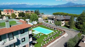 A residential area with a swimming pool, multiple buildings, and a view of the sea.