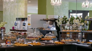 A buffet with various food items, including pastries and desserts, and a coffee machine.
