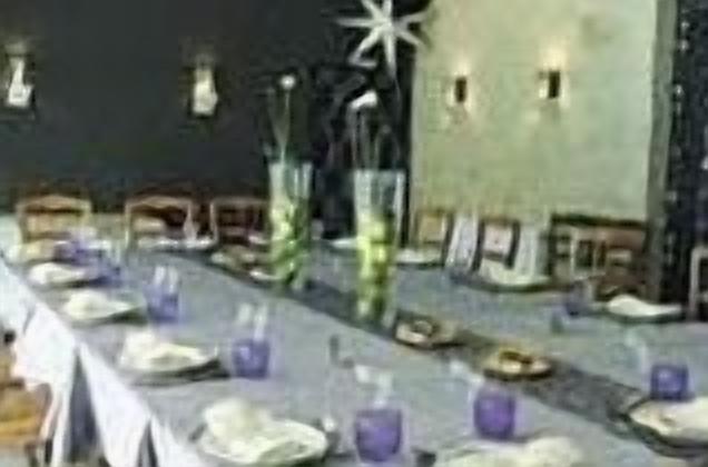 A dining area with a long table set for multiple guests, featuring plates, glasses, and cutlery.