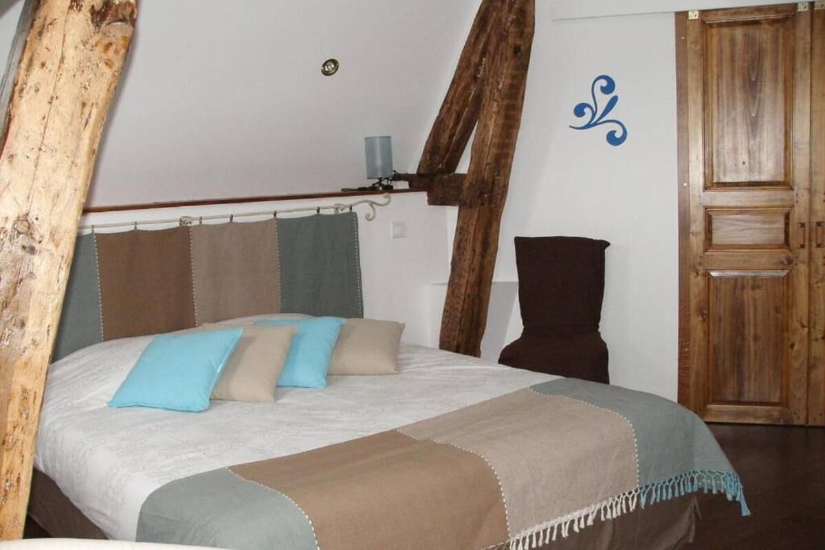 A bedroom with a bed, a wooden door, and a wall with a decorative element.