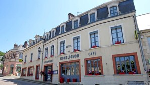 Un edificio con un letrero que dice 'HOTEL DU MONTLIGEON', un letrero de 'RESTAURANT' y un letrero de 'CAFE'.