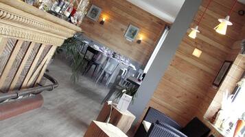 A restaurant with wooden walls, tables, chairs, and hanging pendant lights.