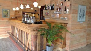 Un rincón de bar con paredes de madera, luces colgantes y estantes llenos de botellas y vasos.