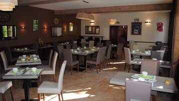 Een restaurant met meerdere tafels en stoelen, in een ruim opgezette ruimte met een betegelde vloer.