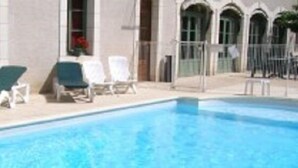 A swimming pool with lounge chairs and a building with arched windows. - Hostellerie du Perigord Vert (Brantôme en Périgord)