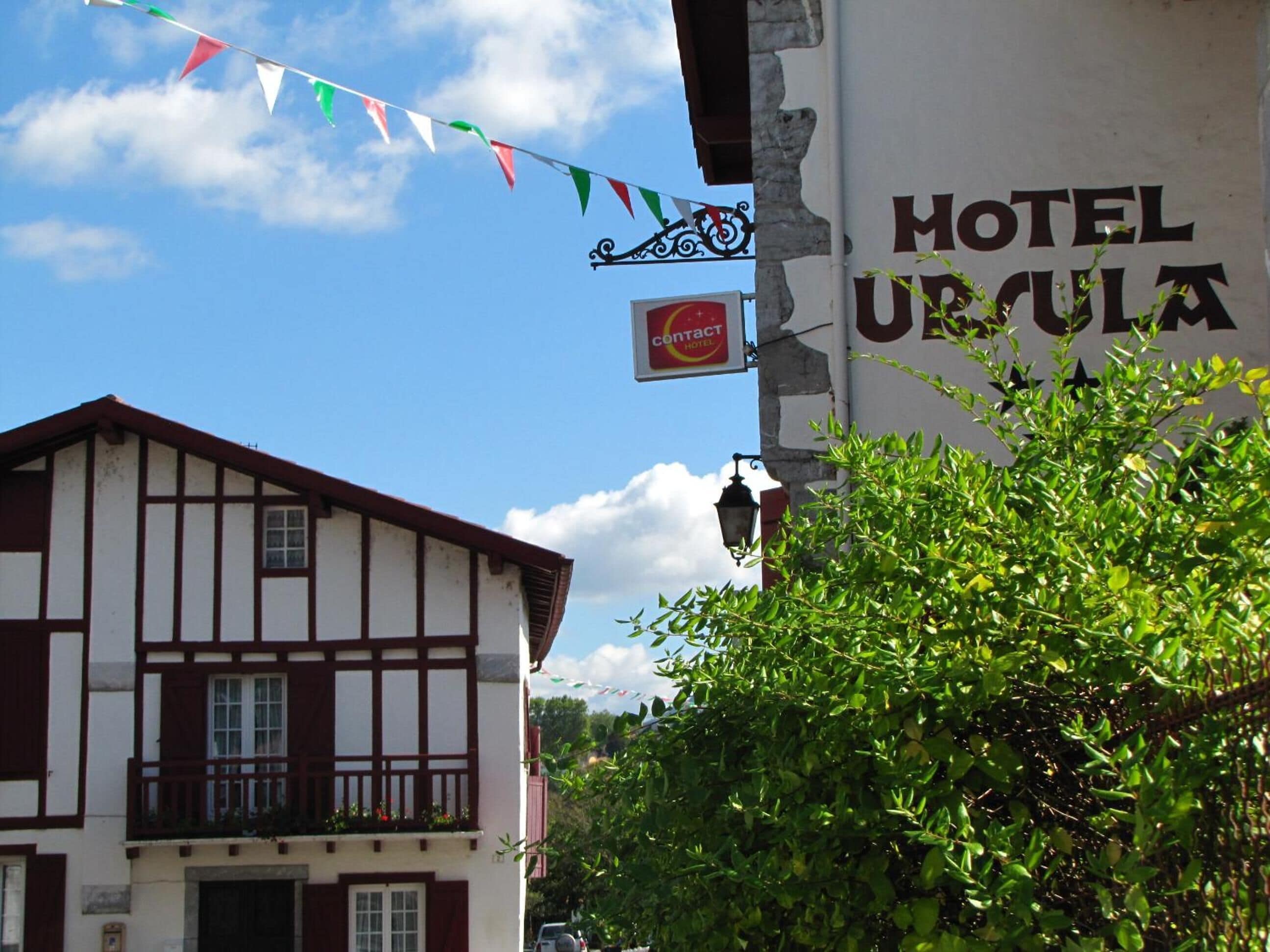 A traditional building with a sign for 'HOTEL URSULA' and a contact sign for 'contact hotel'.