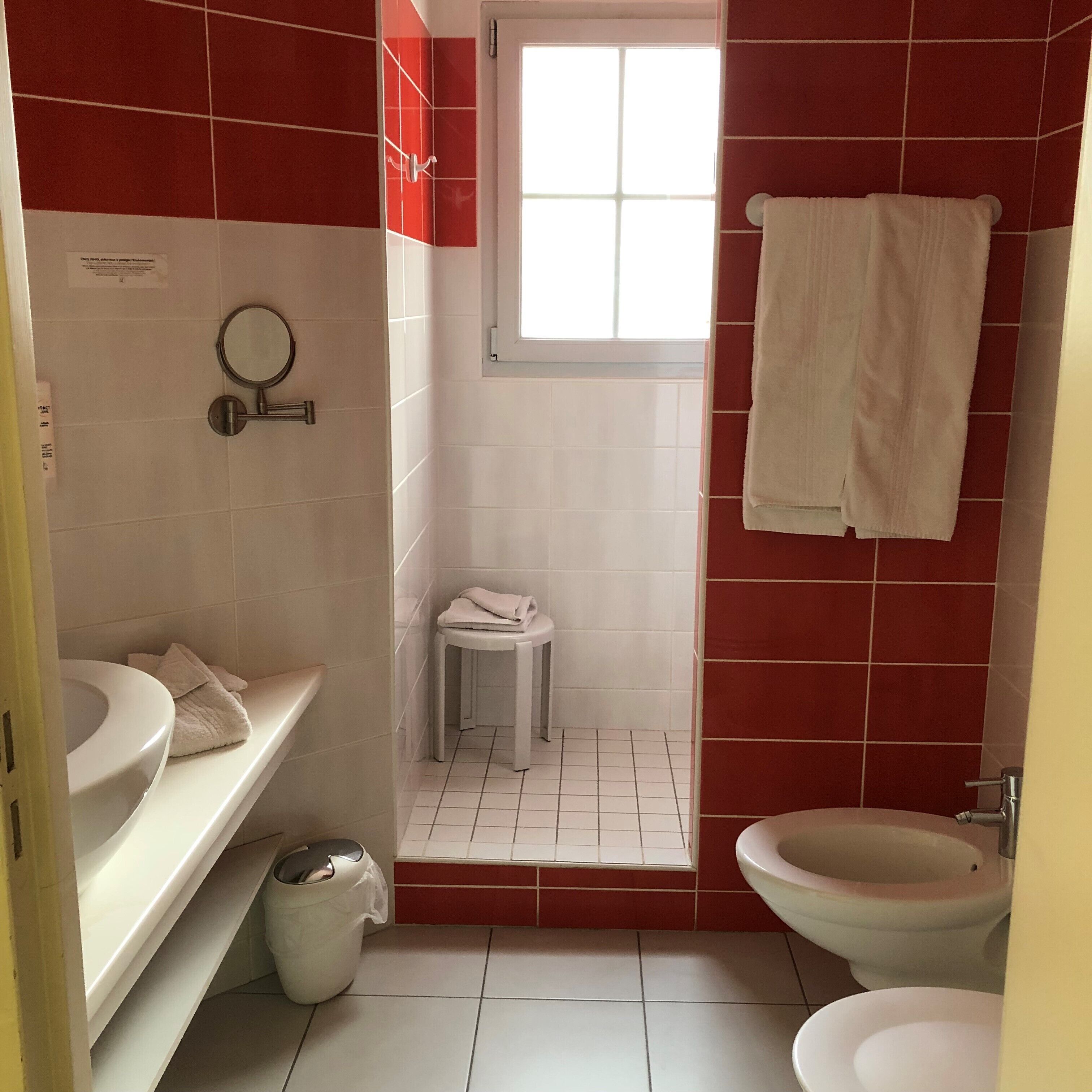 A compact bathroom with a toilet, sink, and a small stool.