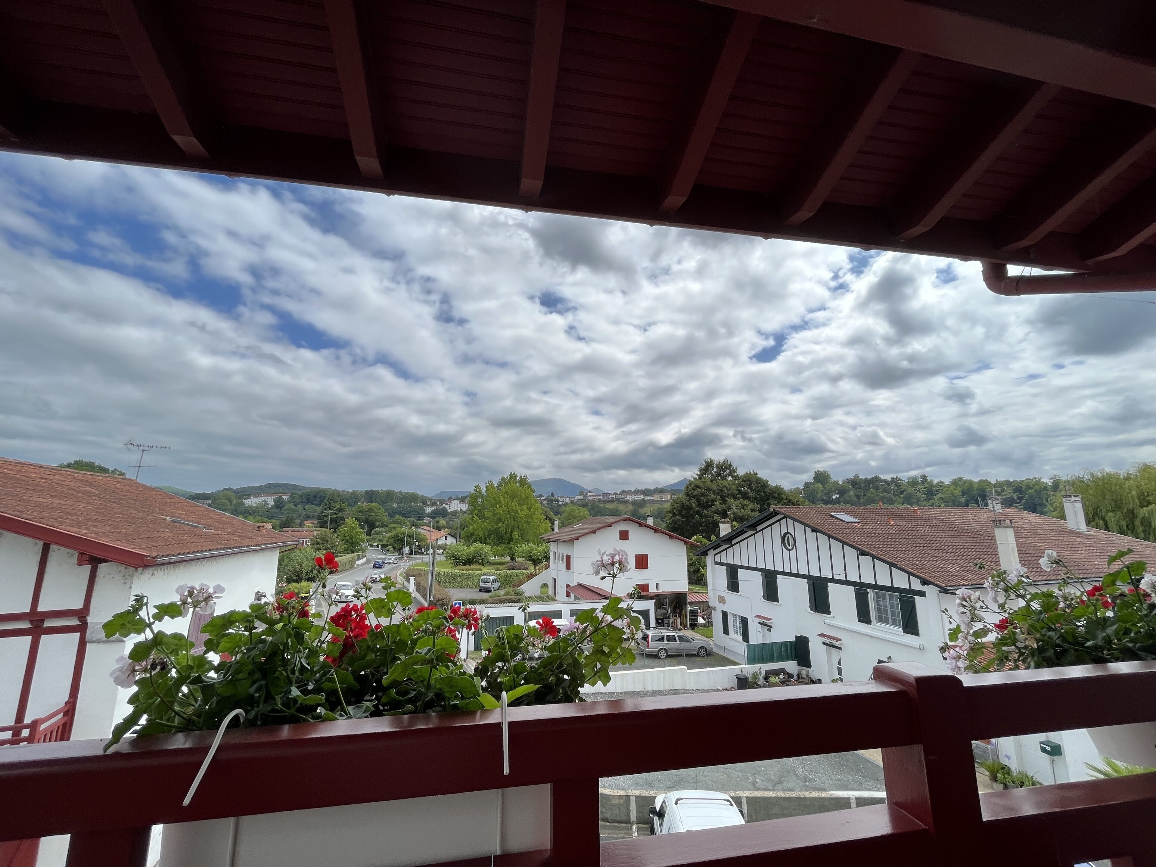 A balcony with a view of a town, including buildings and a mountain in the distance.