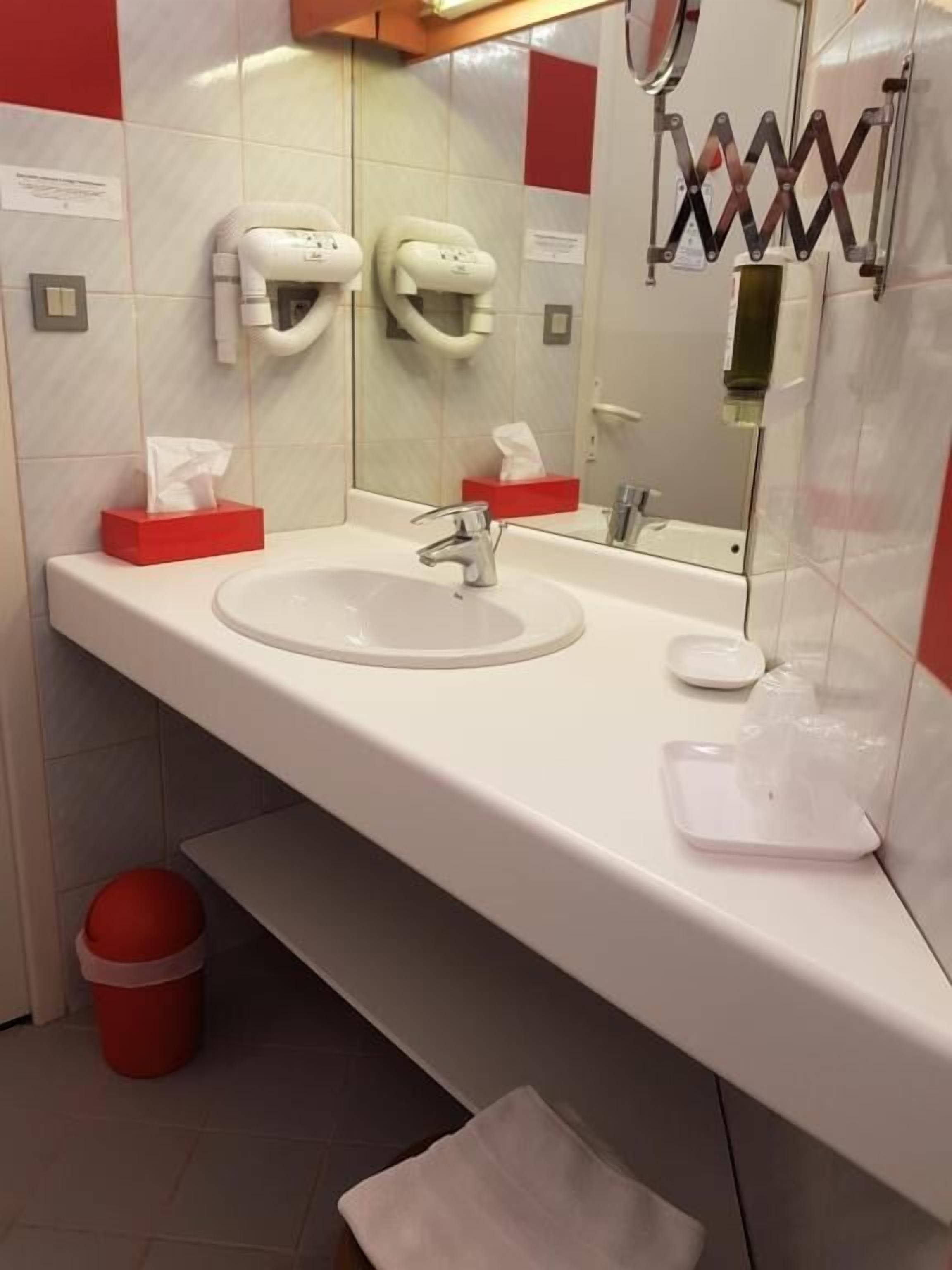 Un baño moderno con un lavamanos blanco, un espejo y dos dispensadores de toallas de papel.