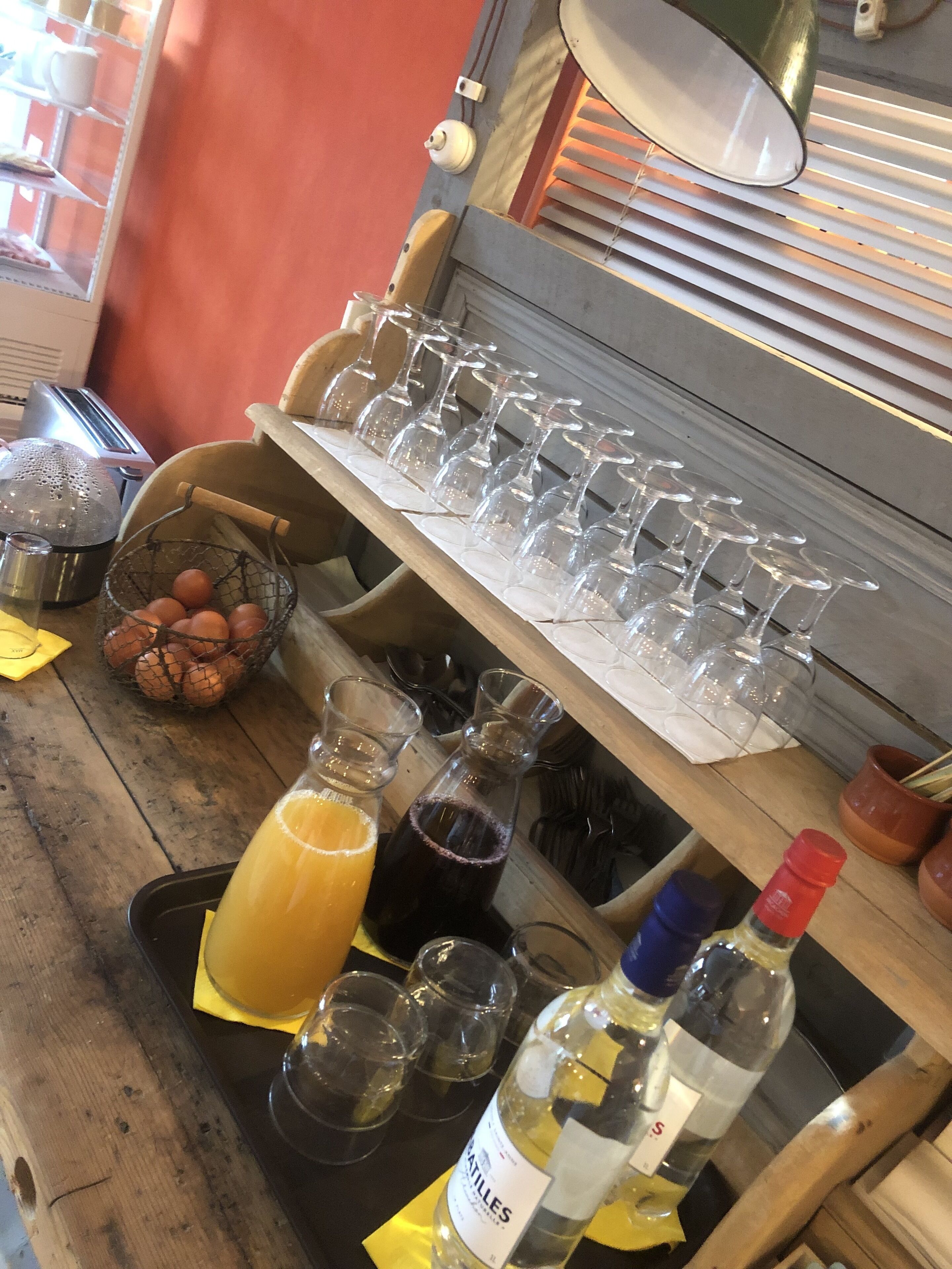 A bar area with glasses, bottles, and a basket of eggs.