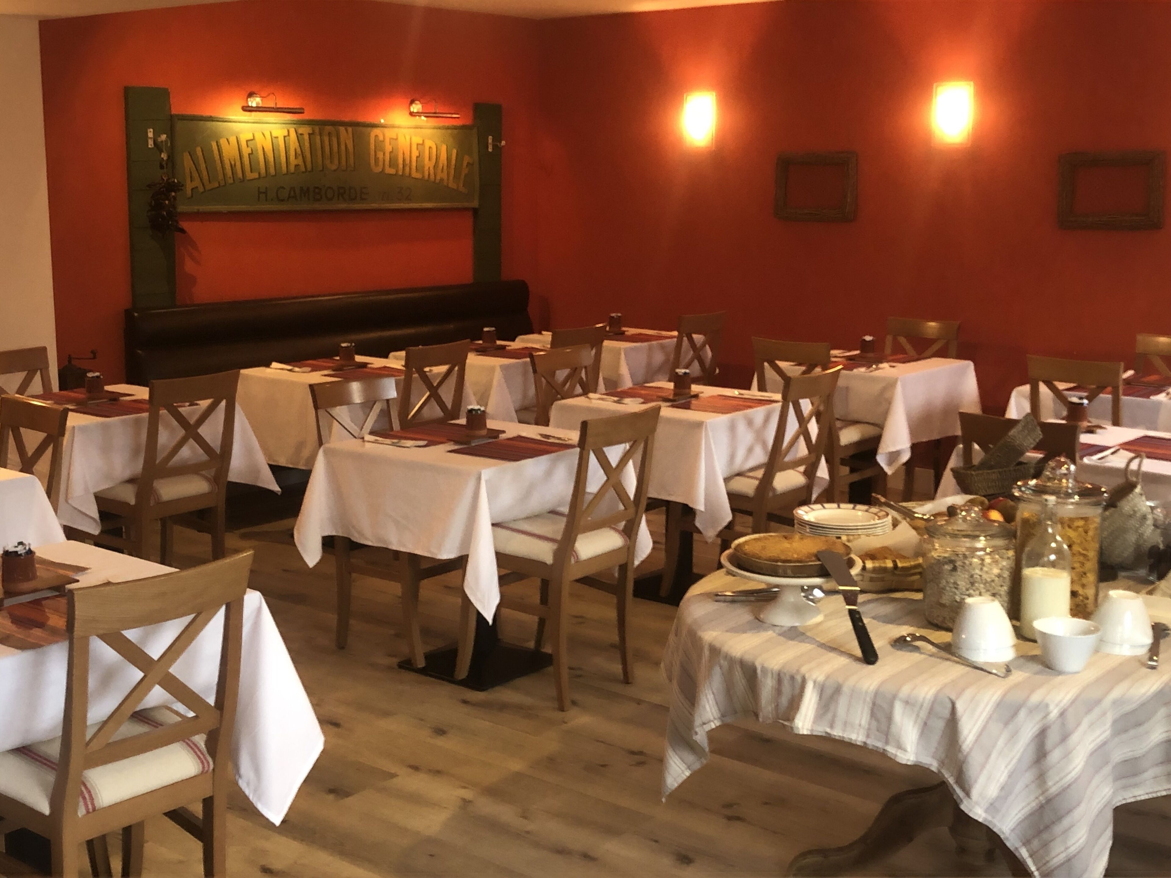 Um restaurante com várias mesas e cadeiras, um letreiro na parede e diversos itens de comida sobre as mesas.