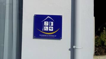 Un edificio con un cartel que indica que es un hotel de 5 estrellas, un letrero de servicios turísticos y para personas con discapacidad, y un área de recepción parcialmente visible.