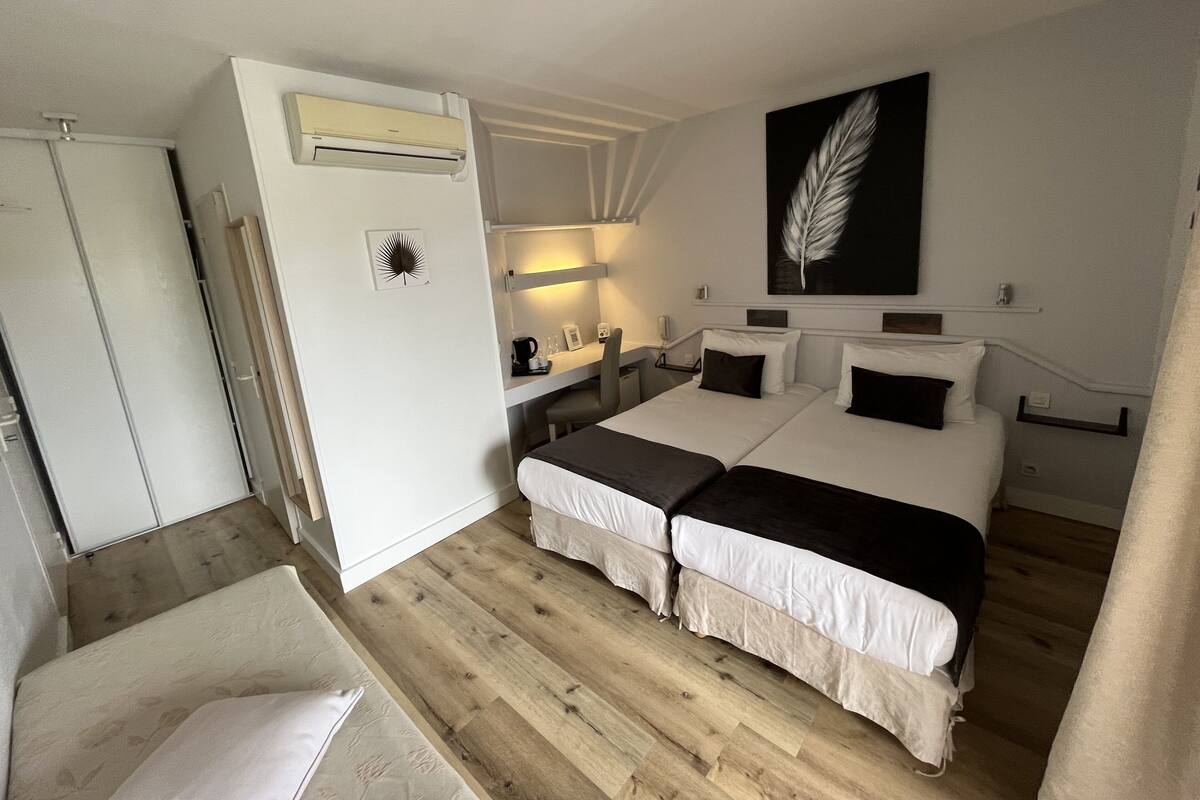 Hotelkamer met twee bedden, een bureau, een stoel, een kledingkast en een grote wanddecoratie van veren.